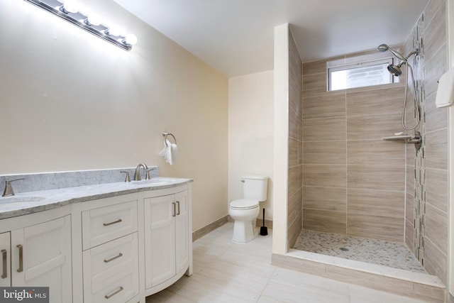 bathroom featuring toilet, tiled shower, and vanity