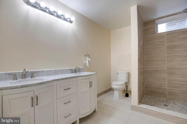 bathroom with toilet, vanity, and tiled shower