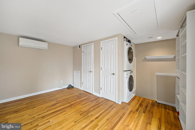 washroom featuring hardwood / wood-style flooring, stacked washer / dryer, and a wall mounted AC