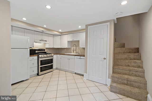 kitchen with sink, white appliances, white cabinets, and light tile patterned flooring