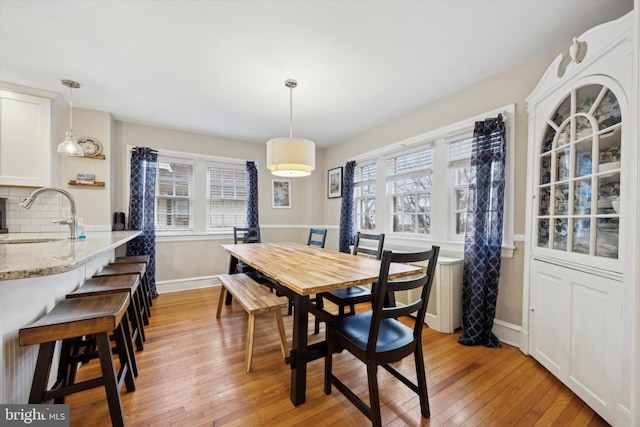 dining room featuring a healthy amount of sunlight, sink, and light hardwood / wood-style flooring