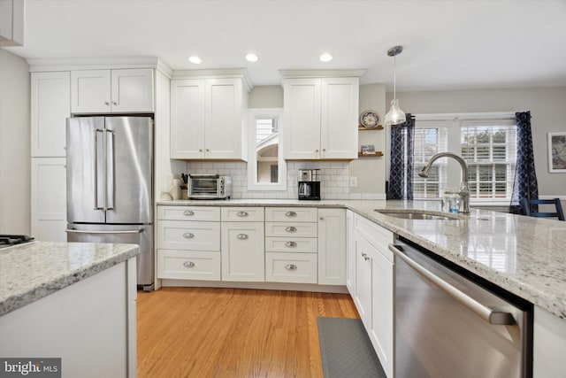 kitchen featuring white cabinetry, appliances with stainless steel finishes, decorative light fixtures, and sink