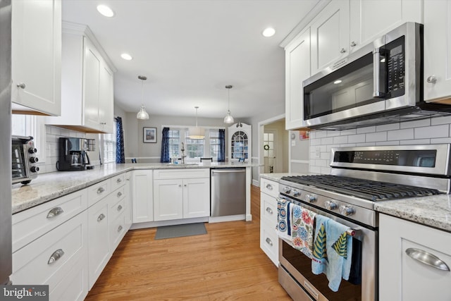 kitchen with white cabinetry, pendant lighting, stainless steel appliances, and kitchen peninsula