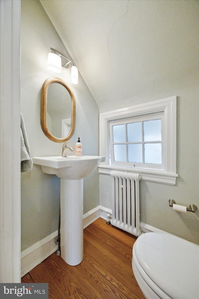 bathroom featuring radiator, vaulted ceiling, hardwood / wood-style floors, and toilet