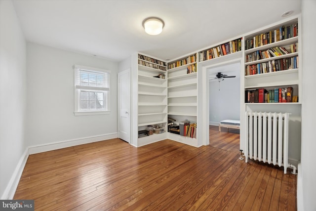 unfurnished bedroom with hardwood / wood-style flooring, radiator, and a closet