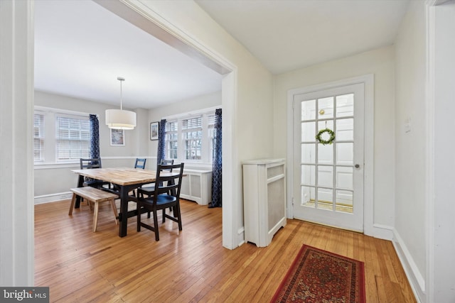 dining space with radiator heating unit, light hardwood / wood-style flooring, and a wealth of natural light