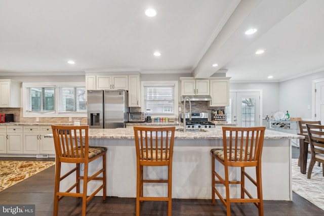 kitchen with dark wood-style floors, plenty of natural light, ornamental molding, and stainless steel refrigerator with ice dispenser