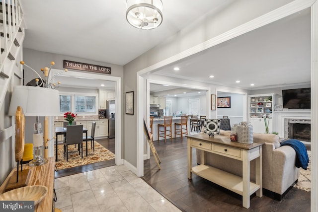 living area with a chandelier, recessed lighting, a fireplace, baseboards, and crown molding