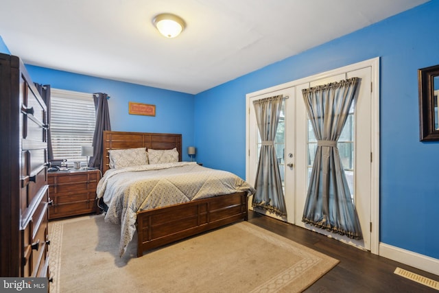 bedroom with french doors, visible vents, baseboards, and wood finished floors