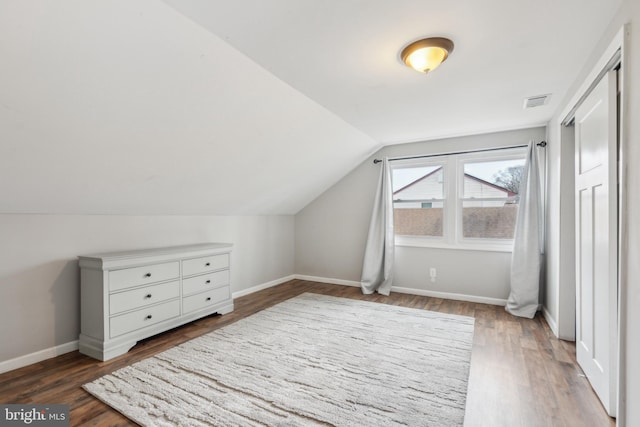 bonus room with lofted ceiling, visible vents, baseboards, and wood finished floors