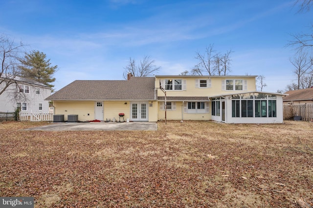 back of property with a sunroom, a fenced backyard, a chimney, french doors, and a patio area