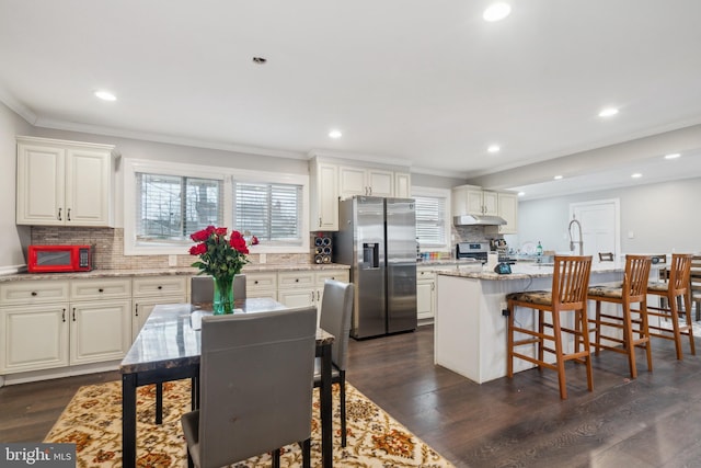 kitchen featuring a breakfast bar, appliances with stainless steel finishes, dark wood finished floors, and crown molding