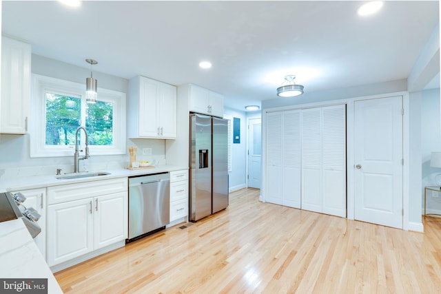 12452 White Horse Rd, Lusby, MD 20657 - kitchen with a sink, hanging light fixtures, appliances with stainless steel finishes, white cabinetry, and light wood-type flooring