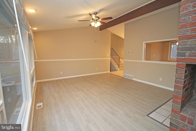 unfurnished living room featuring ceiling fan, lofted ceiling, hardwood / wood-style floors, and a brick fireplace