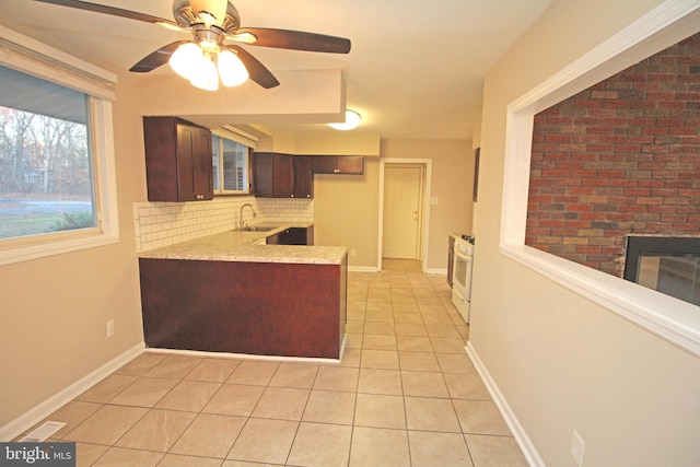 kitchen with sink, a brick fireplace, light tile patterned floors, white range with gas cooktop, and decorative backsplash