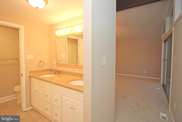 bathroom featuring vanity, tile patterned flooring, lofted ceiling, and toilet