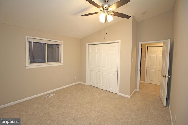 unfurnished bedroom featuring vaulted ceiling, light colored carpet, ceiling fan, and a closet