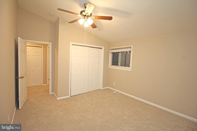 unfurnished bedroom featuring vaulted ceiling, light colored carpet, ceiling fan, and a closet