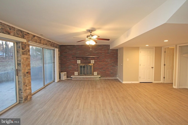 unfurnished living room with a brick fireplace, hardwood / wood-style floors, and ceiling fan