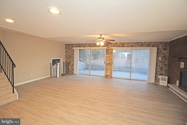 unfurnished living room with hardwood / wood-style flooring, a large fireplace, and ceiling fan