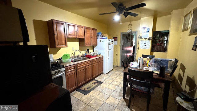 kitchen featuring refrigerator, sink, white refrigerator, ceiling fan, and gas stove