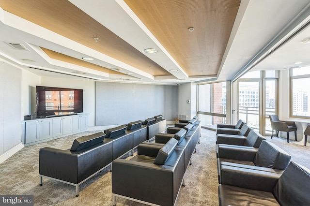 carpeted cinema room featuring wooden ceiling and a raised ceiling