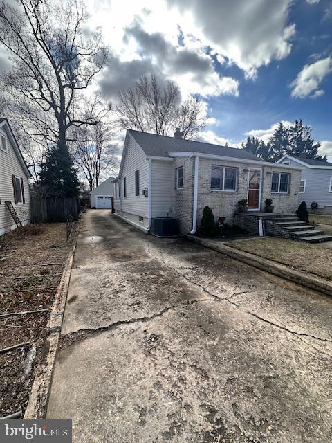 view of front of home with central air condition unit, an outbuilding, fence, concrete driveway, and a chimney