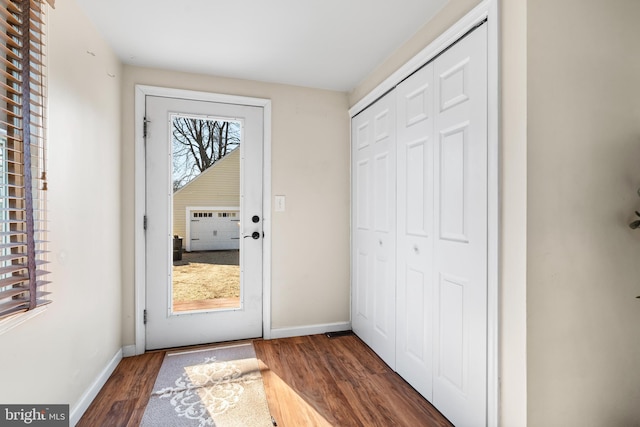 doorway featuring baseboards and wood finished floors