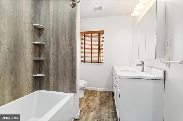 bathroom with vanity, wood finished floors, visible vents, a textured ceiling, and toilet