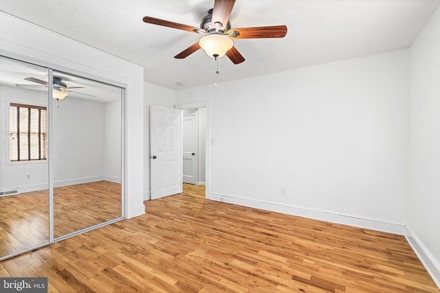 unfurnished bedroom featuring light wood-style floors, baseboards, a closet, and ceiling fan