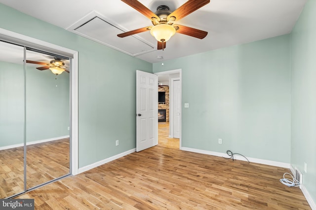 unfurnished bedroom with attic access, wood finished floors, and baseboards