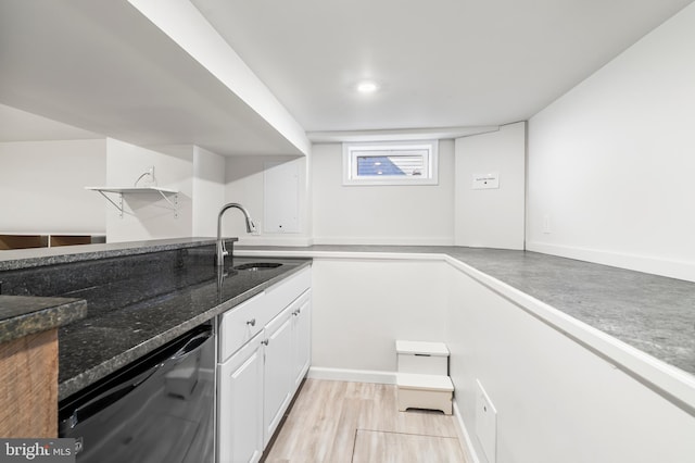 kitchen featuring dishwasher, dark stone counters, light wood-style floors, white cabinetry, and a sink