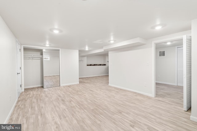 finished below grade area featuring visible vents, baseboards, and light wood-style flooring