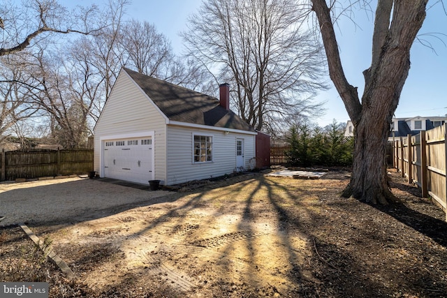 view of home's exterior with a chimney, roof with shingles, a garage, and fence