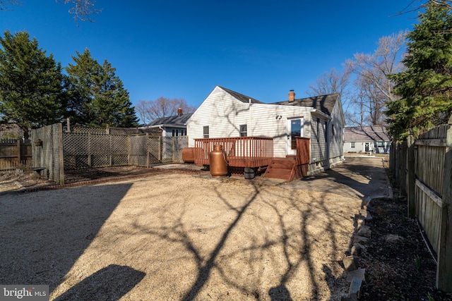 rear view of house with a deck, fence, and a chimney