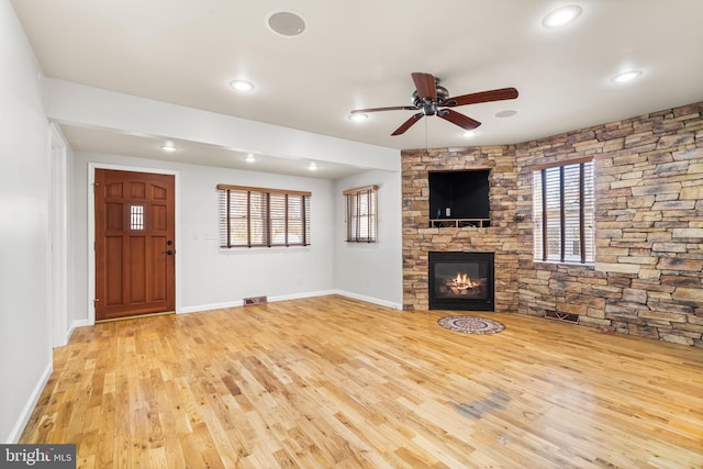 unfurnished living room with visible vents, a fireplace, a ceiling fan, and wood finished floors