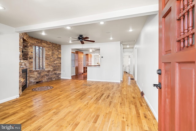 unfurnished living room with a ceiling fan, a fireplace, baseboards, and light wood finished floors