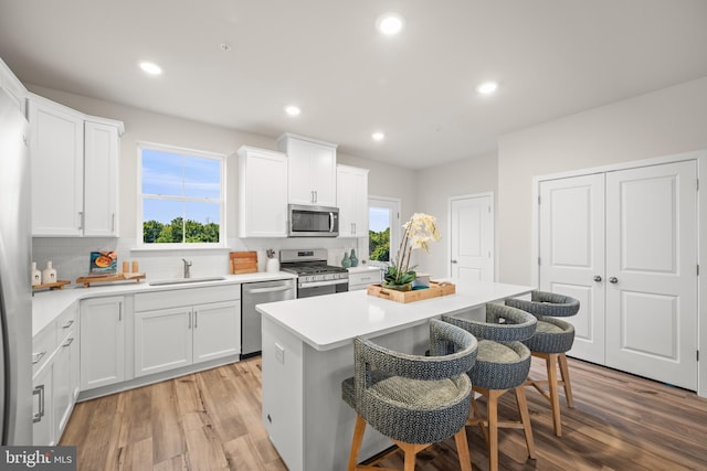 kitchen with appliances with stainless steel finishes, a center island, white cabinets, and a kitchen breakfast bar