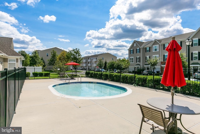 community pool with a residential view, fence, and a patio