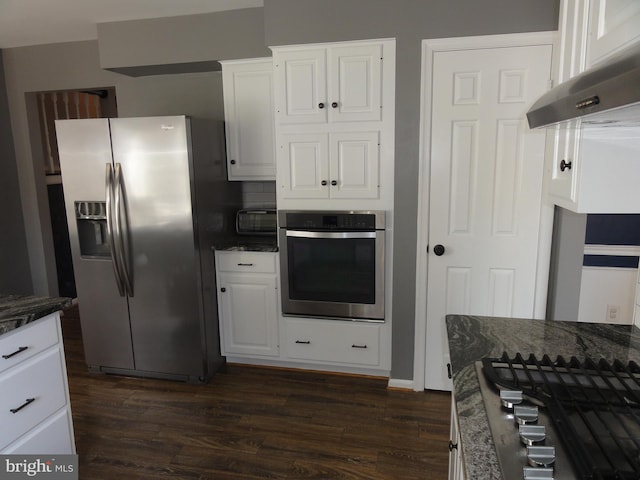 kitchen with dark wood-type flooring, appliances with stainless steel finishes, dark stone countertops, and white cabinets