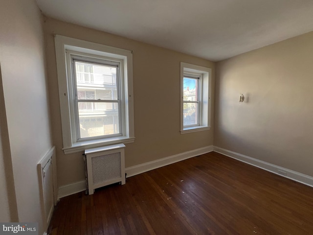 spare room with dark wood-type flooring and radiator heating unit