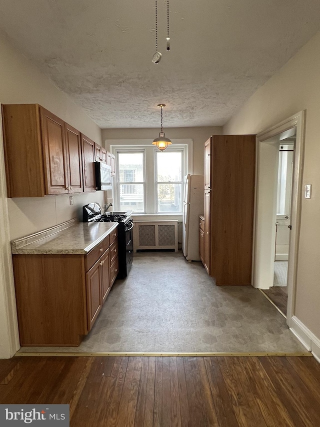 kitchen featuring hardwood / wood-style flooring, black gas range, white refrigerator, a textured ceiling, and decorative light fixtures