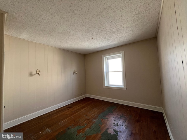 empty room with dark hardwood / wood-style flooring and a textured ceiling