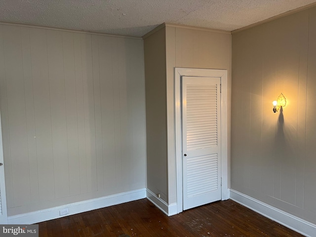 interior space with dark wood-type flooring, ornamental molding, and a textured ceiling