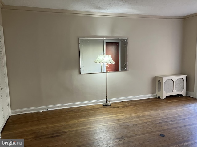 spare room featuring dark wood-type flooring and ornamental molding