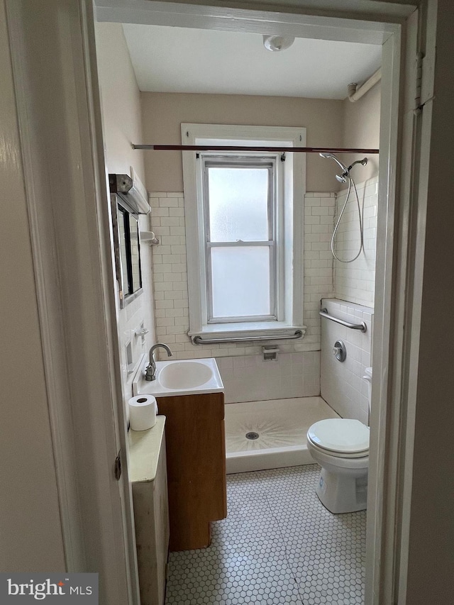 bathroom featuring vanity, toilet, and a tile shower