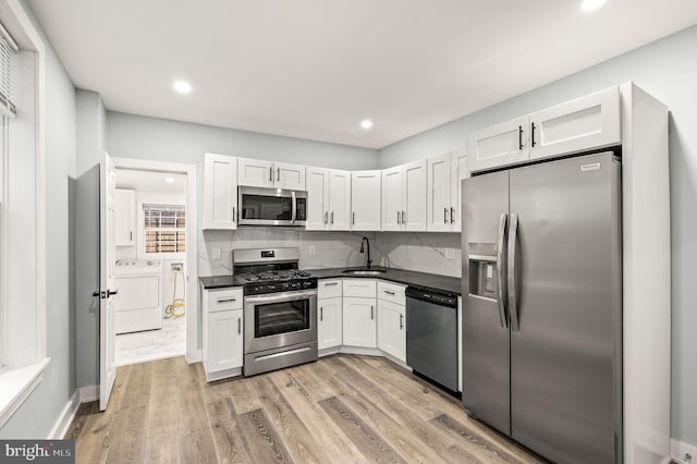 kitchen featuring separate washer and dryer, light hardwood / wood-style floors, white cabinets, and appliances with stainless steel finishes