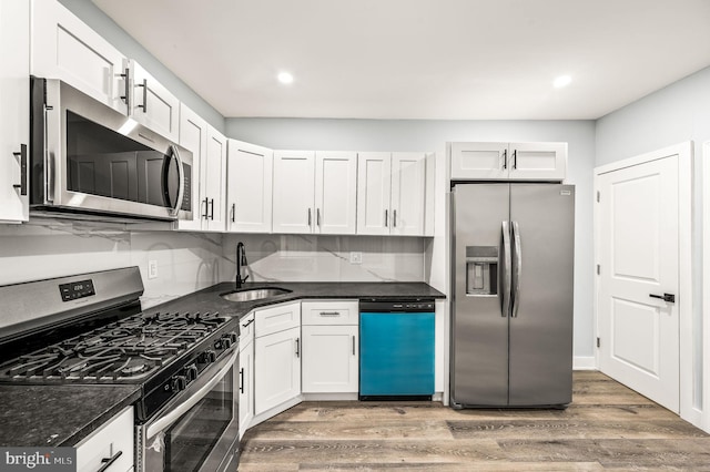 kitchen featuring hardwood / wood-style floors, tasteful backsplash, white cabinetry, sink, and stainless steel appliances