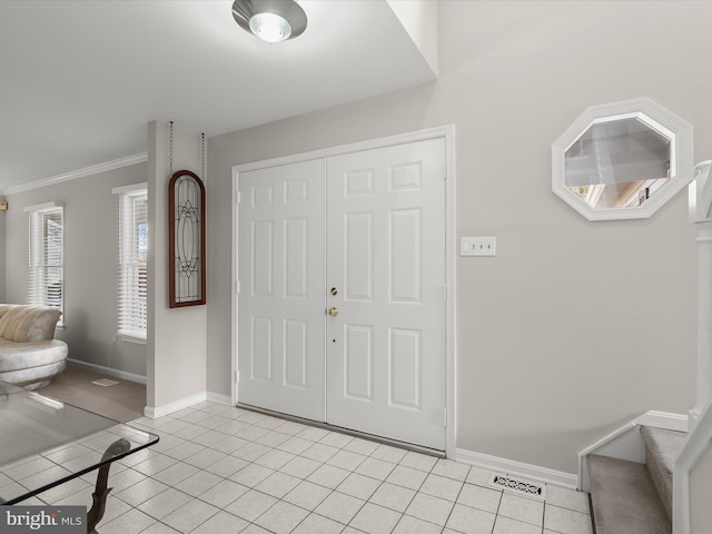 foyer entrance featuring crown molding, light tile patterned flooring, visible vents, and baseboards