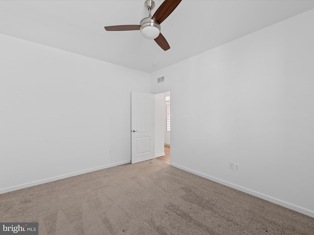 carpeted spare room with a ceiling fan, visible vents, and baseboards